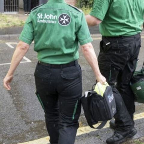 Back of two volunteer first aiders on a road carrying their equipment bags.